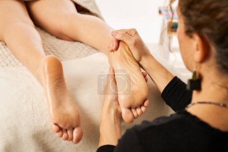 Photo for A woman reflexotherapy practitioner performing rehabilitation on a patient - Royalty Free Image