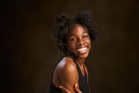 Foto de Retrato de una hermosa joven negra sonriente afro chica con el pelo negro rizado. Ella está con los brazos cruzados - Imagen libre de derechos
