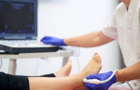Foto de Un fisioterapeuta que realiza un ultrasonido en el tobillo para verificar si hay lesión - Imagen libre de derechos