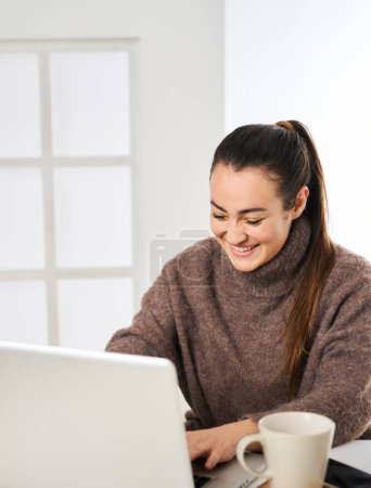 Photo for A smiling woman working energetically on her personal computer from her office at work - Royalty Free Image