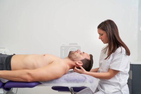 Téléchargez les photos : Un homme recevant un traitement de migraine au cabinet du physiothérapeute - en image libre de droit