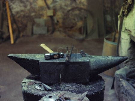 Foto de Desde arriba de martillo y pinzas colocadas en yunque de acero masivo en viejo taller herrero tradicional de mala calidad - Imagen libre de derechos