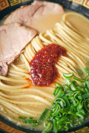 Téléchargez les photos : Soupe japonaise aux nouilles avec tranches de porc et oignons de printemps frais hachés dans un bol - en image libre de droit