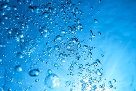 Textur abstrakter Luftblasen unterschiedlicher Größe auf dem Hintergrund des Gefälles lebendigen azurblauen Wassers