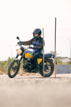 Foto de Vista lateral del nivel del suelo del motociclista en casco de seguridad a caballo motocicleta moderna en el motodromo con obstáculos de metal - Imagen libre de derechos