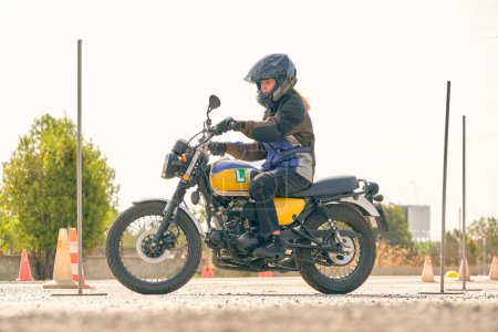 Foto de Vista lateral a nivel del suelo de la motociclista femenina en motocicleta con conos - Imagen libre de derechos
