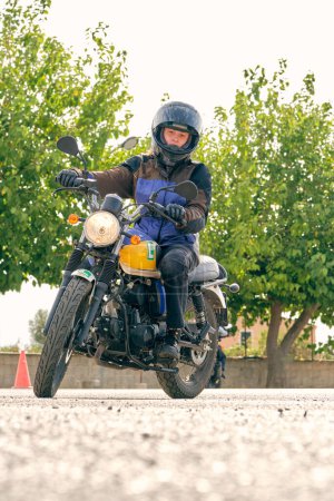 Foto de Nivel del suelo de la hembra en el casco de conducción de motocicleta moderna durante la lección sobre el aeródromo - Imagen libre de derechos