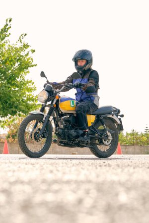 Foto de Vista lateral de la motociclista femenina en casco montando motocicleta contemporánea durante la lección en el aeródromo - Imagen libre de derechos