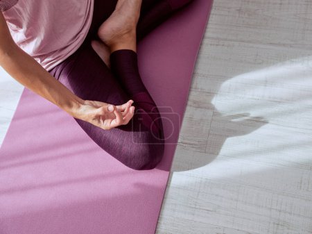 Photo for From above of unrecognizable female athlete in sportswear practicing yoga taking lotus pose on mat - Royalty Free Image