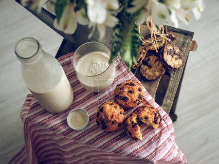 Foto de Desde arriba de botella de vidrio de leche y pastelería deliciosa colocada en caja de madera con flores - Imagen libre de derechos