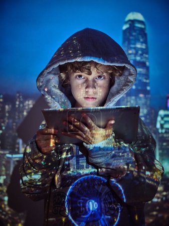 Foto de Niño con capucha gris mirando a la cámara y el uso de la tableta digital, mientras que de pie en la proyección de la noche megápolis - Imagen libre de derechos