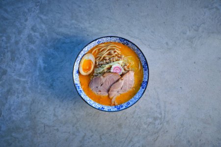 Foto de Vista superior de la carne de cerdo char siu y narutomaki en tazón de sopa de ramen apetitoso con fideos y huevo colocado en la mesa - Imagen libre de derechos