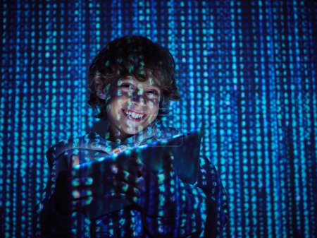 Photo for Smiling kid hacking digital tablet while standing in dark room with programming symbols - Royalty Free Image