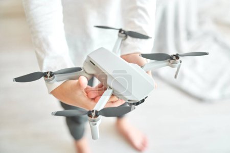 Téléchargez les photos : De dessus de la récolte sans visage garçon préadolescent montrant nouveau drone avec caméra vidéo et exploité avec télécommande - en image libre de droit