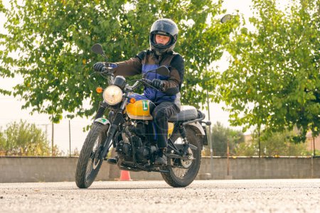 Téléchargez les photos : Niveau de sol du motard féminin concentré dans le casque de moto d'équitation sur l'asphalte moto - en image libre de droit