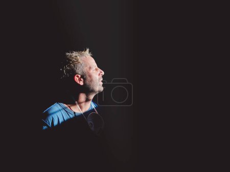 Photo for Side view of bearded shaper putting off protective respiratory mask and resting with closed eyes and breathing fresh air at window - Royalty Free Image
