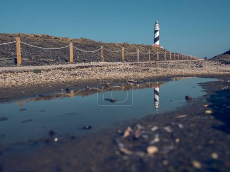 Photo for Picturesque scenery of empty pathway leading to white lighthouse tower located on hill in countryside under cloudless blue sky in daytime - Royalty Free Image