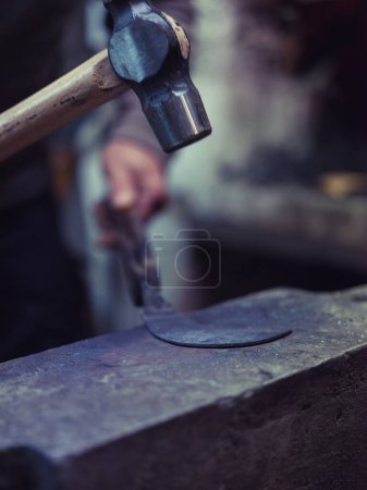 Photo for Closeup of crop anonymous blacksmith using hammer while forging metal on old anvil in traditional workshop - Royalty Free Image