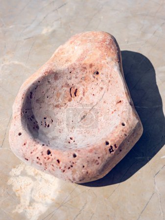 Foto de Vista superior de la artesanía decorativa de piedra hecha de sólido cuenco de roca en forma desigual colocado sobre fondo gris - Imagen libre de derechos