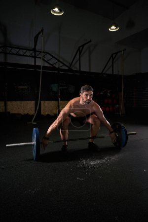 Photo for Full body of focused athletic male ready to lift with barbell while doing deadlift exercise in spacious gym - Royalty Free Image