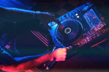 Foto de Desde arriba manos de la cosecha irreconocible DJ reproducción de música en el moderno reproductor de CDJ mientras trabaja en discoteca con equipo musical - Imagen libre de derechos