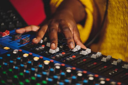 Photo for High angle of crop anonymous female sound engineer in yellow sweater working on mixing console - Royalty Free Image