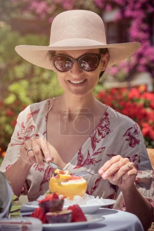 Photo for Stock photo of happy woman eating fruit in the garden during sunny day. - Royalty Free Image