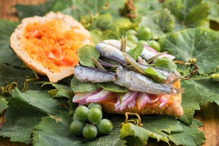 Offenes Erntesandwich mit Sardinen, Fleisch und verschiedenen Gemüsesorten auf einem Weinblatt. Gastronomie der Kanarischen Inseln