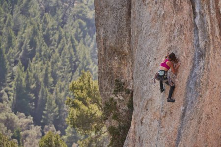 Téléchargez les photos : Vue de dos corps complet d'alpiniste active anonyme avec harnais de sécurité escalade pente rocheuse pendant l'entraînement dans la nature - en image libre de droit