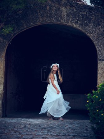 Téléchargez les photos : Vue latérale complète du corps de la jeune femme en robe blanche et chapeau debout près du passage voûté regardant vers le haut - en image libre de droit