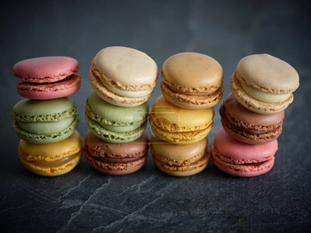 Photo for Set of different flavored multicolored macaroons with filling placed on top of each other on gray table in light room - Royalty Free Image