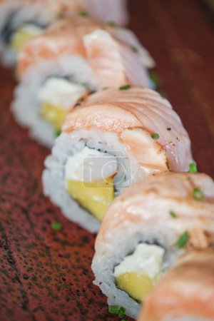 Téléchargez les photos : Photo de stock de délicieuses bouchées de sushi avec du saumon et des graines au restaurant japonais. - en image libre de droit
