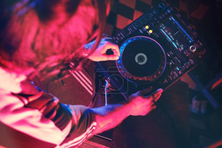 Foto de Desde arriba de la cosecha anónima talentoso DJ reproducción de la canción en el moderno reproductor de CDJ mientras se trabaja en discoteca con poca iluminación - Imagen libre de derechos