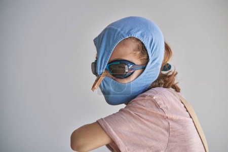 Téléchargez les photos : Enfant se protégeant avec des shorts de bain et des lunettes contre une éventuelle infection - en image libre de droit