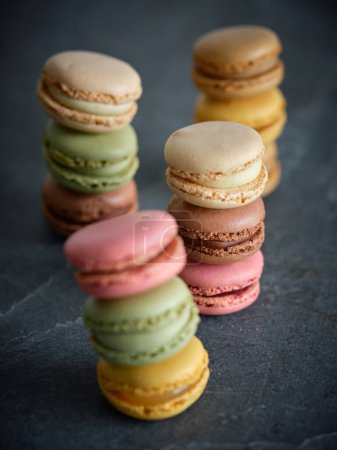 Photo for Set of delicious sweet multicolored macaroons with different flavors stacked on top of each other on gray table in room - Royalty Free Image