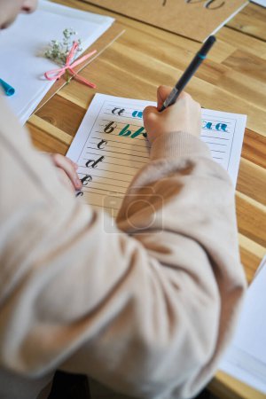 Photo for From above of unrecognizable person drawing letters on paper sheet using colorful marker in creative workspace - Royalty Free Image