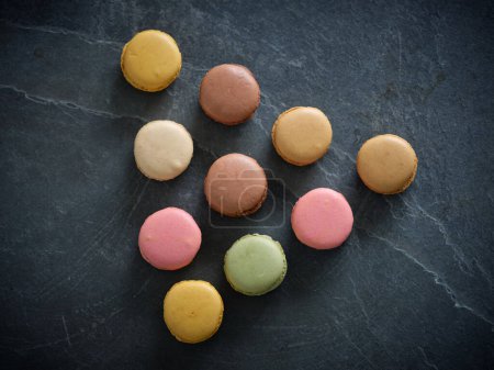 Foto de Conjunto vista superior de macarrones dulces con diferentes sabores colocados sobre fondo gris en forma de pirámide en sala de luz - Imagen libre de derechos