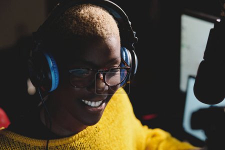 Photo for From above of cheerful young African American female radio host in glasses and headphones near microphone broadcasting live - Royalty Free Image