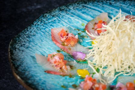 Foto de Apetitiva comida asiática con rábano daikon rallado servido en plato redondo contra atún y verduras frescas picadas - Imagen libre de derechos