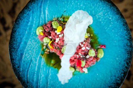 Photo for Top view of delicious red tuna tartare with wasabi decorated with herb served on plate with prawn cracker in restaurant - Royalty Free Image