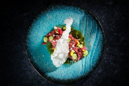 Photo for Top view of delicious sophisticated raw tuna tartare served on plate with white prawn cracker on table in light room - Royalty Free Image
