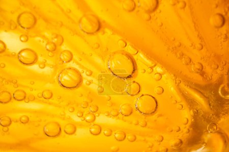 Foto de Primer plano marco completo de rodaja de naranja fresca en deliciosa ginebra alcohólica transparente y cóctel tónico con pequeñas burbujas en la sala de luz - Imagen libre de derechos