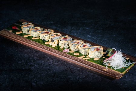 Téléchargez les photos : D'en haut de savoureux rouleaux de sushi uramaki japonais servis sur plateau avec sauce sésame à la lumière sur la surface du marbre - en image libre de droit