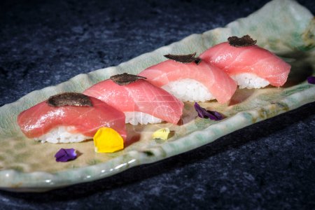 Foto de Alto ángulo de sushi apetitoso con atún y arroz servido en el plato cerca de pétalos de flores - Imagen libre de derechos