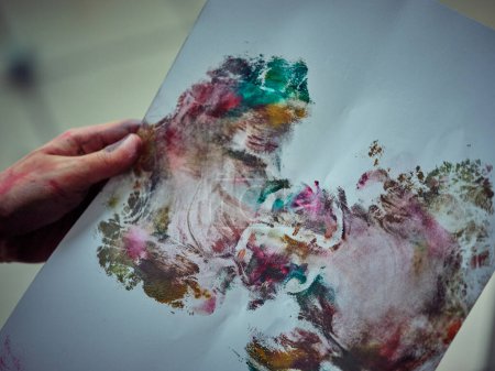 Foto de Artista creativo irreconocible con la mano sucia de papel de retención de pintura con dibujo abstracto colorido que se asemeja a la mariposa - Imagen libre de derechos