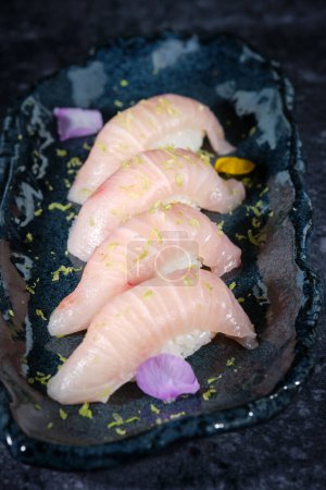 Foto de Alto ángulo de sushi hecho de carne de pescado cruda con arroz y colocado en un plato negro - Imagen libre de derechos