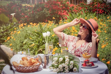 Foto de Foto de la mujer feliz tomando el sol y disfrutando del desayuno en el jardín. - Imagen libre de derechos