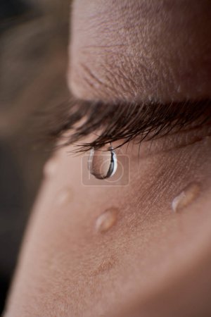Foto de Primer plano cerrado ojo de cosecha anónima niño disgustado con lágrimas en la mejilla y las pestañas de pie en la sala de luz en casa - Imagen libre de derechos