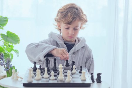 Téléchargez les photos : Concentré adorable garçon préadolescent se préparant mouvement avec pion tout en jouant au jeu d'échecs à bord - en image libre de droit