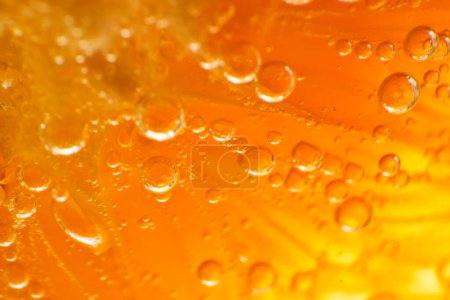 Téléchargez les photos : Gros plan plein cadre de tranche d'orange en gin alcoolisé transparent et boisson tonique avec petites bulles rondes dans la pièce lumineuse - en image libre de droit